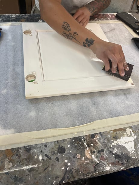 Painter cleaning cabinet door with a scotch pad.