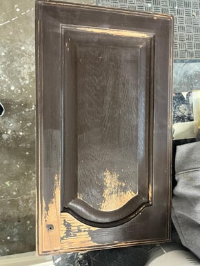 Dark wooden cabinet door with chipped and peeled paint.