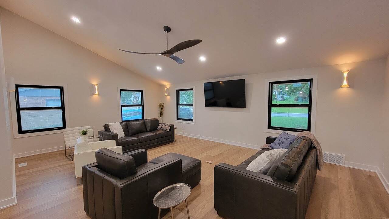Living room with white interior wall paint and ceilings with dark black furniture and accents inside a renovated home in Omaha, NE.