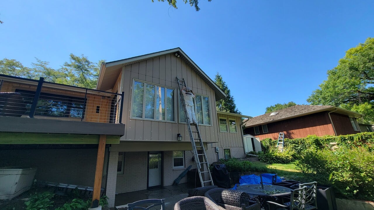 Exterior of house in Omaha, NE with a ladder against it in the process of being painted by Brush & Roll Painting.