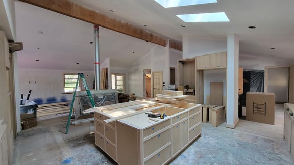 Kitchen and living room in the process of being painted and flooring being installed.