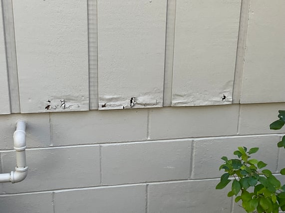 Damaged exterior siding on a home painted off grey in Omaha, NE.