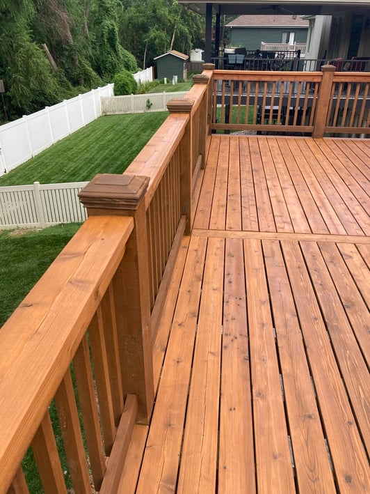 Wood porch on the back of a home stained with a warm orangey tone stain in Omaha, NE.