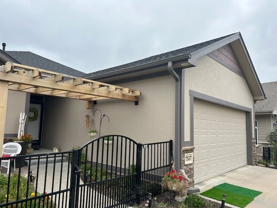 Exterior of house with beige exterior paint with a maroon peak and black trim.