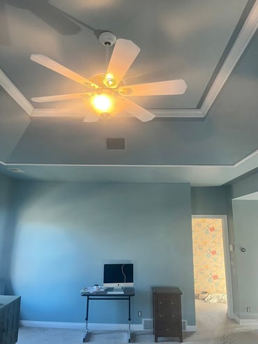 Bedroom walls and ceiling painted blue with white trim on the ceiling and a fan in the center.