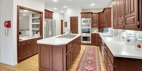 Large kitchen with medium brown stained cabinets and white counters.