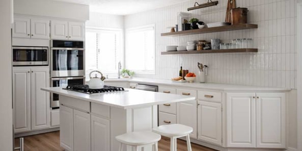 Kitchen with white cabinets and countertops, backsplash and walls.