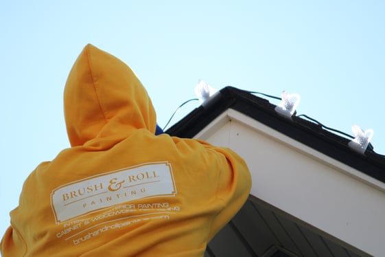 Brush & Roll Painting painter installing christmas lights on the roofline of a home in Omaha, NE.