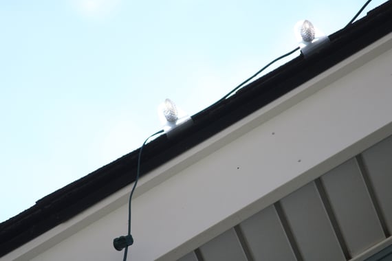 Gutter and roof of a house with Christmas lights being installed.