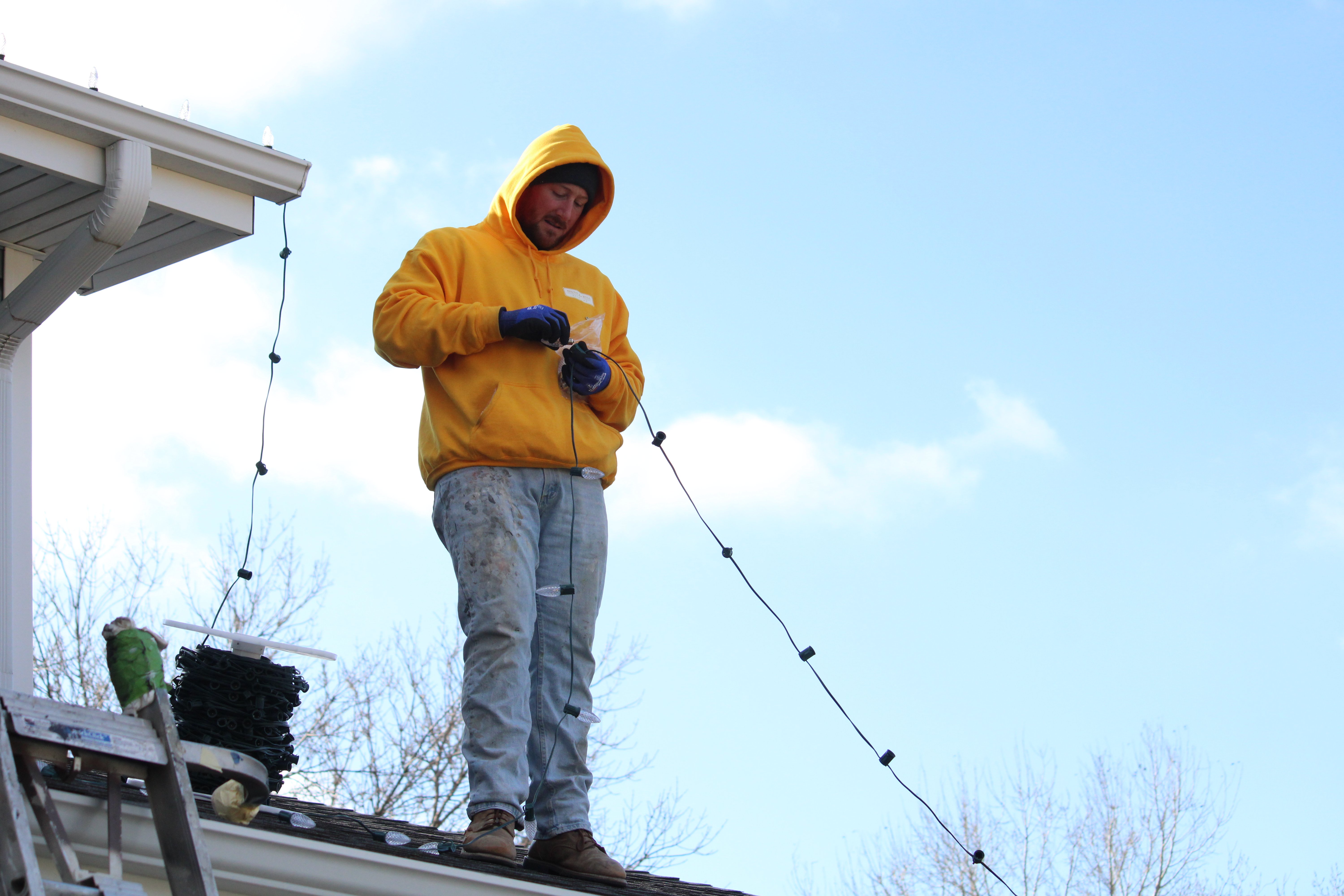 Painter installing Christmas Lights on the outside of a home in Papillion, NE.