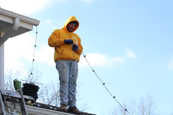 Brush & Roll Painting owner Joe Carlson hanging a strand of c9 bulbs on a home in Omaha, NE.
