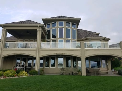 Backside of exterior of large home with windows and deck.