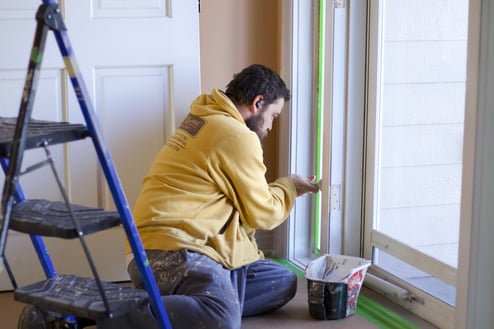 Brush & Roll Painting painter brushing white paint onto door trim opening in Omaha, NE.