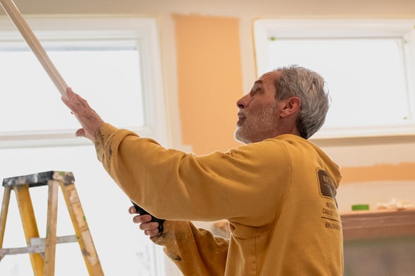 Painter rolling white paint onto walls inside a home in Omaha, Nebraska.
