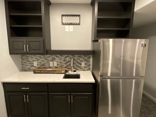 Basement kitchen with dark cabinets painted in a black color with silver handles.