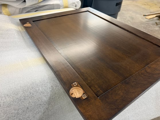 Back of cabinet door with circle slot hinges and the wood is stained a dark brown.
