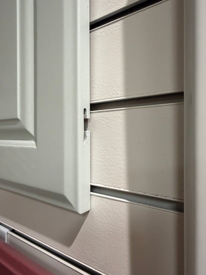 T slot hinge on a cabinet door painted light blue.