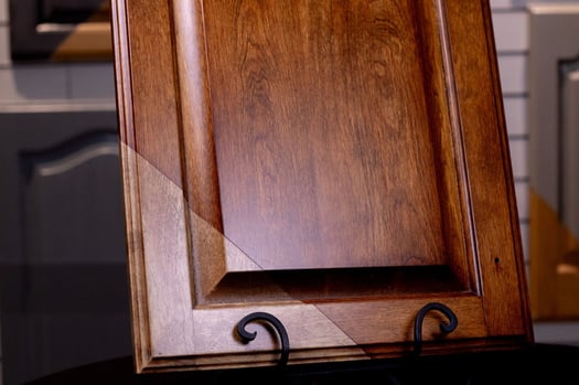 Oak cabinet door showing half refinished with a stain and half left natural.