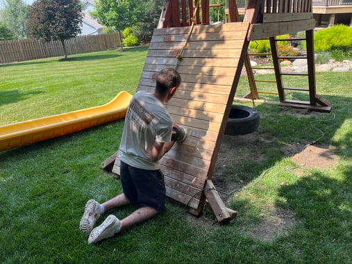 Brush & Roll Painting painter sanding outdoor playset outside of a home in Omaha, NE.