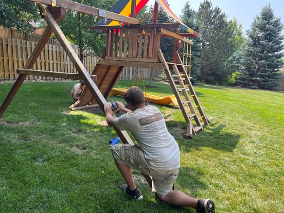 Brush & Roll Painting painter sanding off old stain on a childrens backyard playground set in Omaha, NE before sanding.