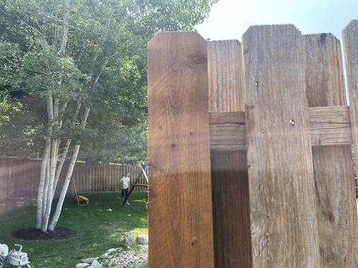 One post on wooden fence stained with warm brown color and bear wood on the rest.