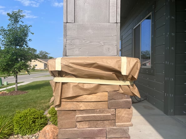 Exterior pillar outside of home with paper and tape to protect it from paint.