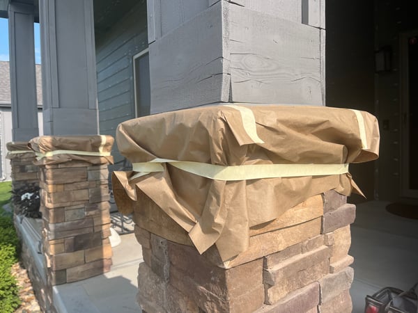Stone and wood pillars with paper and tape on them to protect them from paint.