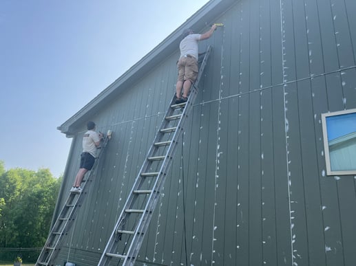 Brush & Roll Painting painters caulking exterior of home along siding board gaps.