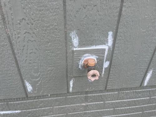 Water spout on the side of a home with caulk around the edges.