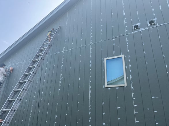 Gaps along siding on the exterior of green painted home filled with caulk.