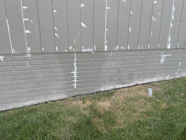 Green painted house with white caulk in gaps and holes before painting in Omaha, NE.