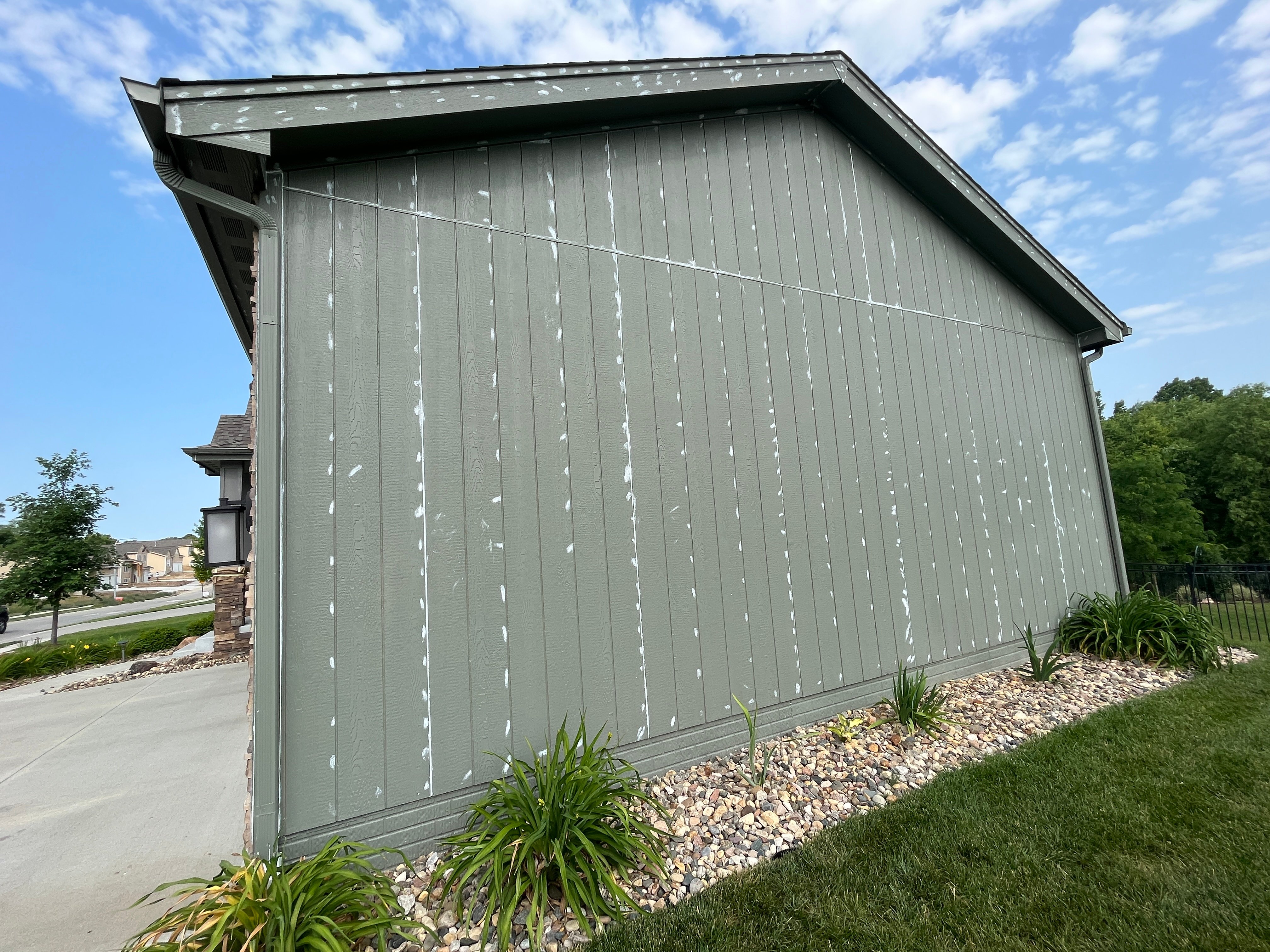Sage green painted house with lots of white caulk in gaps and in sunken nail holes before re painting the home in Omaha, NE.