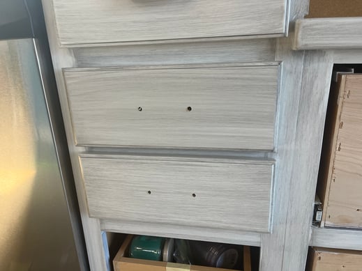 White cabinet drawers with a grey glaze brushed overtop.