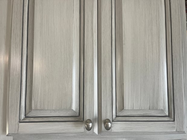 Kitchen cabinets painted white with a grey glaze overtop and in corners.