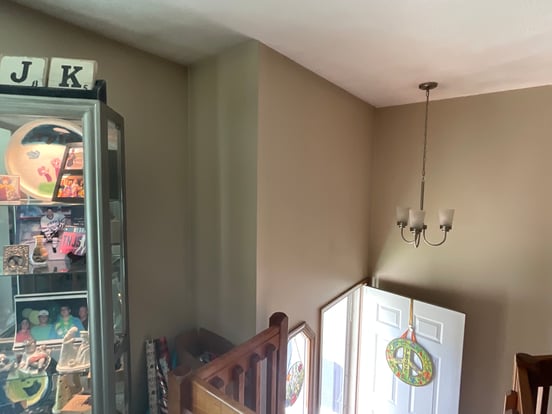 Front entryway of a home with dark beige walls and white ceiling with dark shadow spots over walls due to bad ventilation.