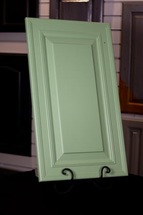 Cabinet door in a light green color on a stand after painting.