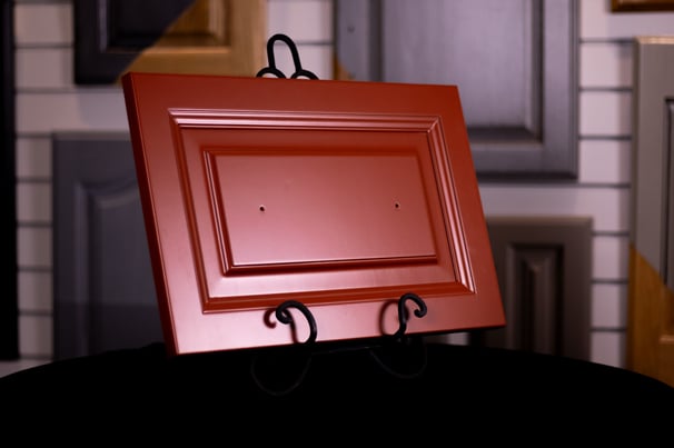 Cabinet door painted a warm red color, completely hiding the wood grain on the door.