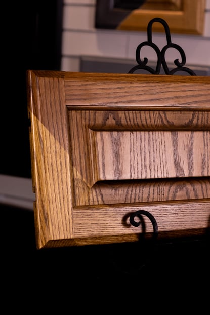 Cabinet door frant showing before and after staining with a warm brown color.