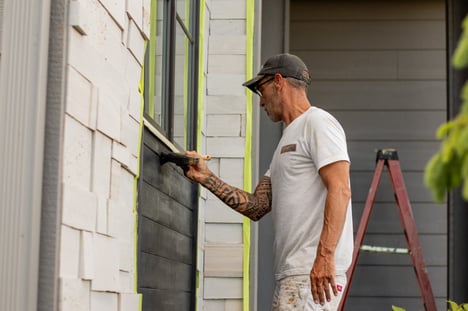 Brush & Roll Painting Painter painting exterior of home black with a brush on siding.