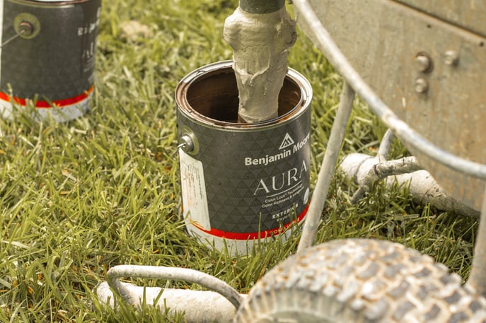 Paint being pumped into a paint sprayer for exterior painting with Benjamin Moore Aura exterior paint.