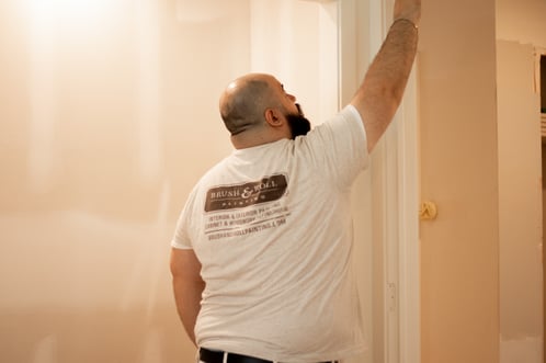 Painter working on a nail hole in a piece of trim on a door frame.