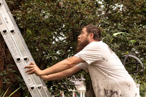 Brush & Roll Painting painter climbing up a ladder against the side of a house in Omaha, NE.