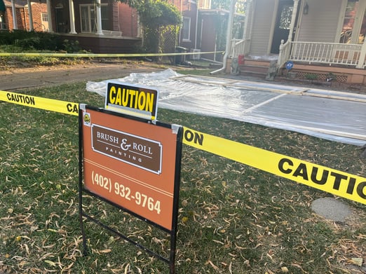 Brush & Roll Painting yard sign with caution tape around a house with painting exterior lead paint in Omaha.