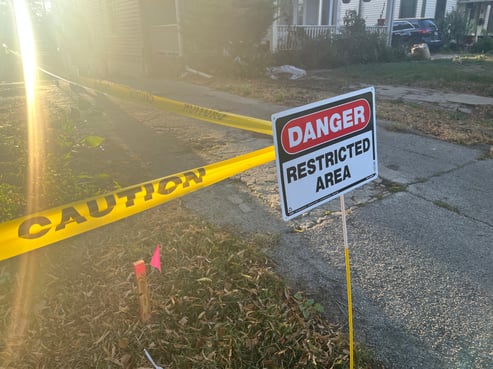"Danger Restricted Area" sign in the front yard of a home with exterior paint being removed and caution tape.