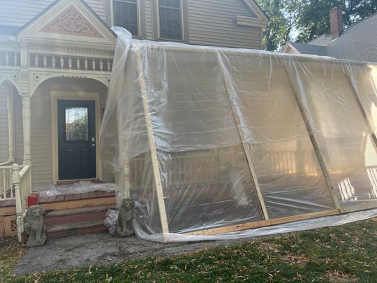 Exterior of house shielded off with a board and plastic structure for lead painting.