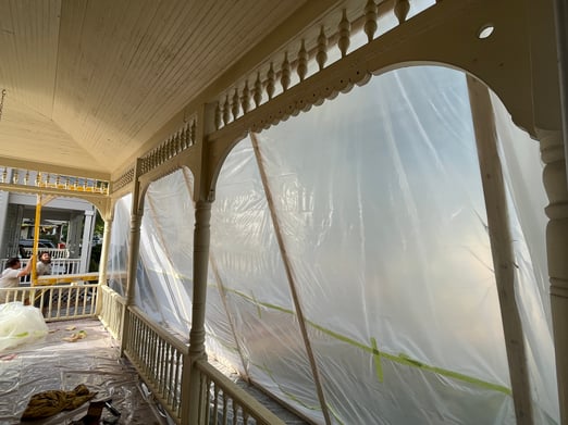 Porch area of house surrounded by plastic tarp for lead paint safety.