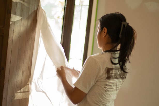 Painter putting up plastic to block off areas before painting inside a home in omaha.
