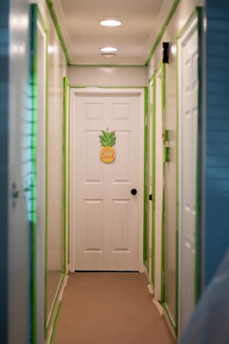 Freshly painted walls and interior doors in a hallway in a Omaha home with green painters tape around all of the door frames and trim.