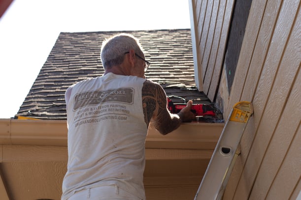 Painter doing siding repairs on exterior of house before painting in Omaha, NE.