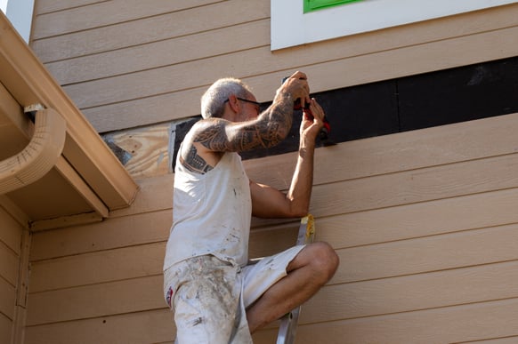 Brush & Roll Painting painter replacing a wooden siding board on the exterior of a house in Omaha, NE.
